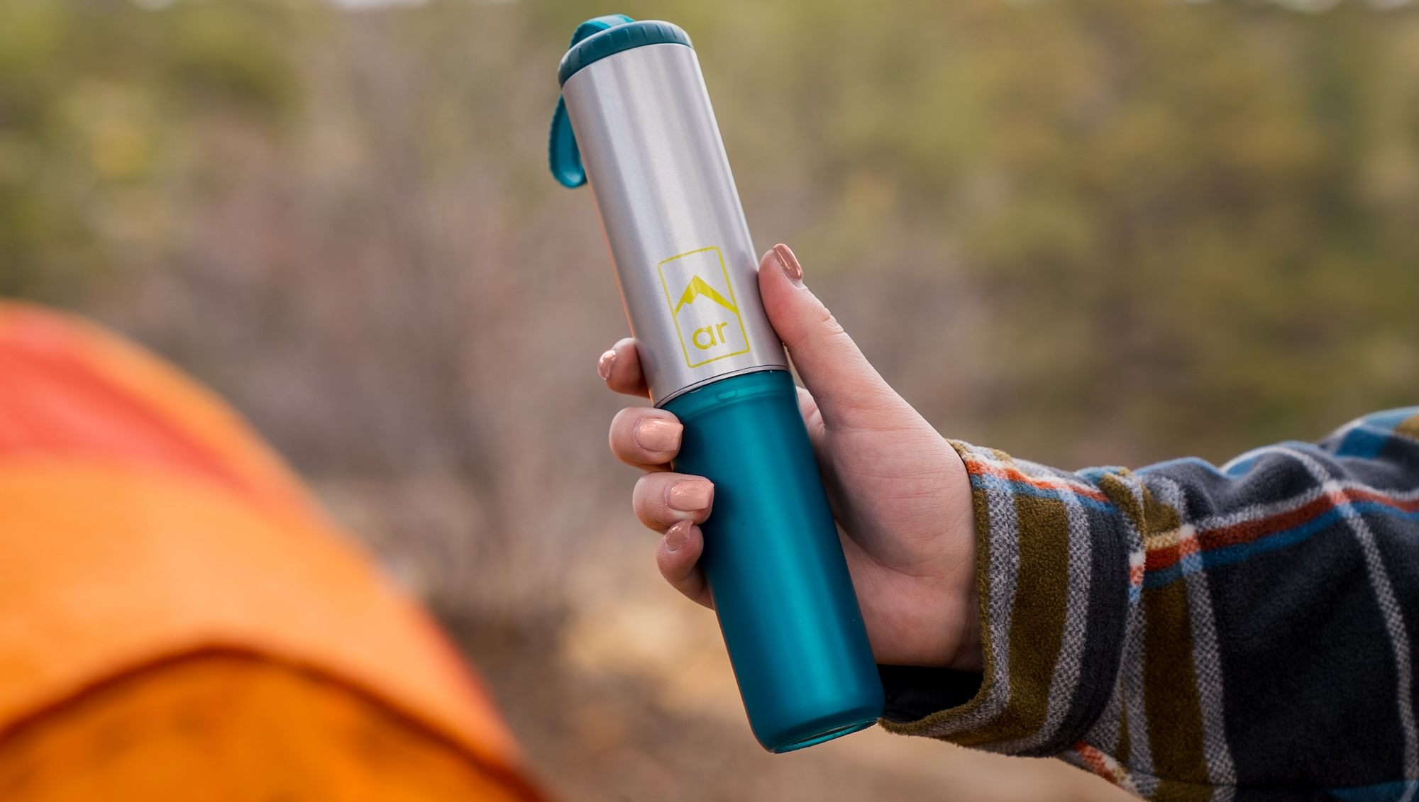 Woman holding the Toilet Trowel in front of an orange tent