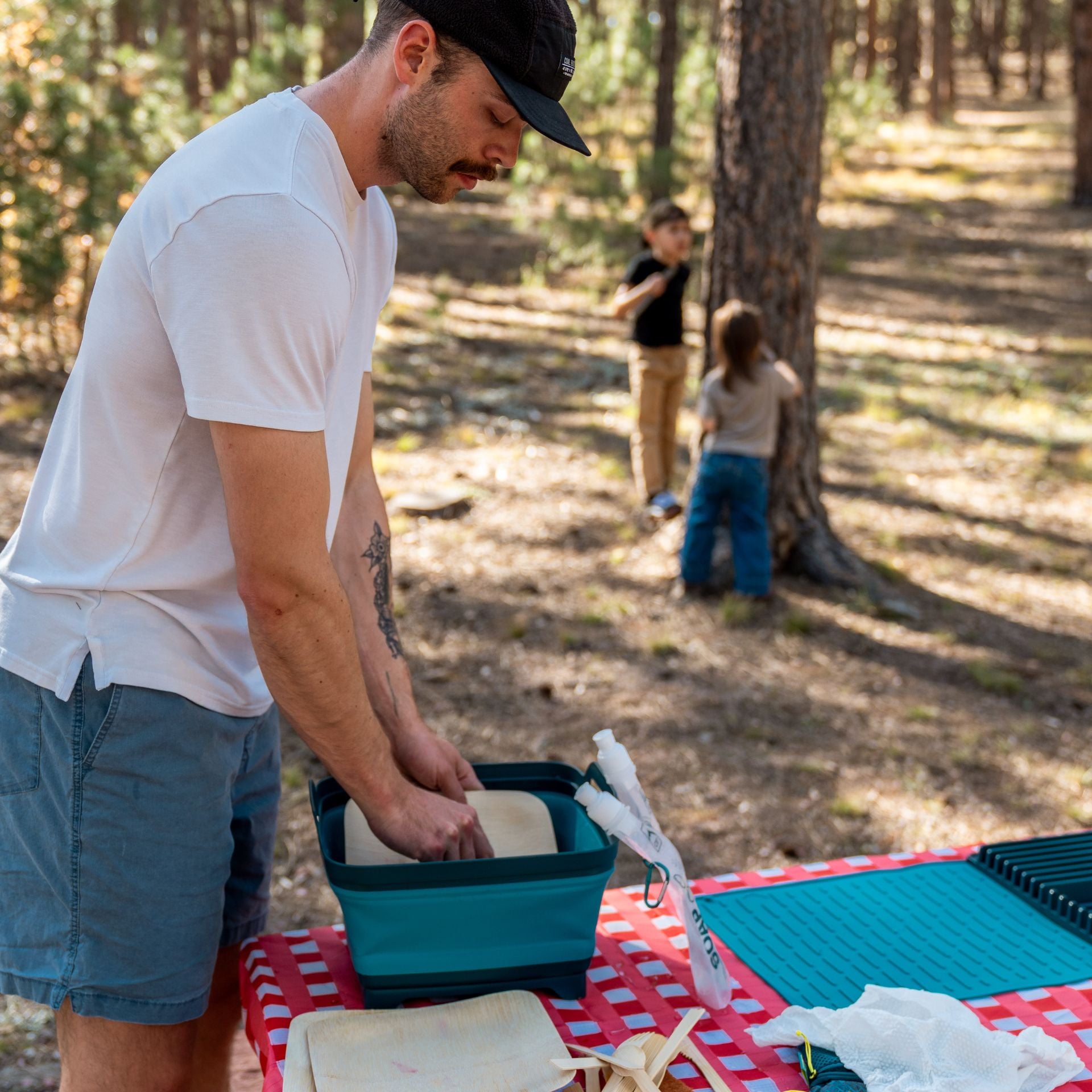 Man washing dishes with the Collapsible Sink while children play in the background