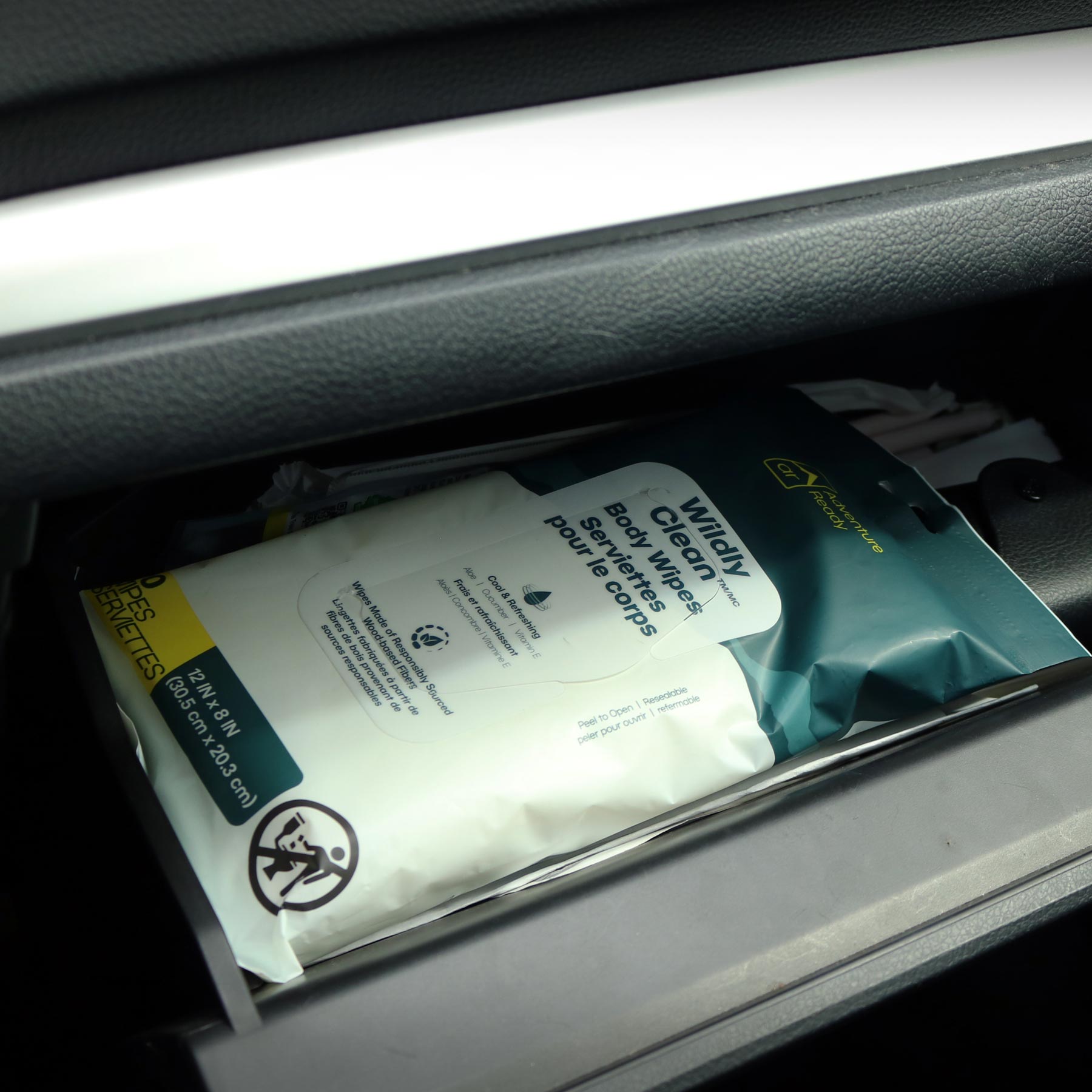 A pack of Adventure Ready Wildly Clean Body Wipes in a car glove box.