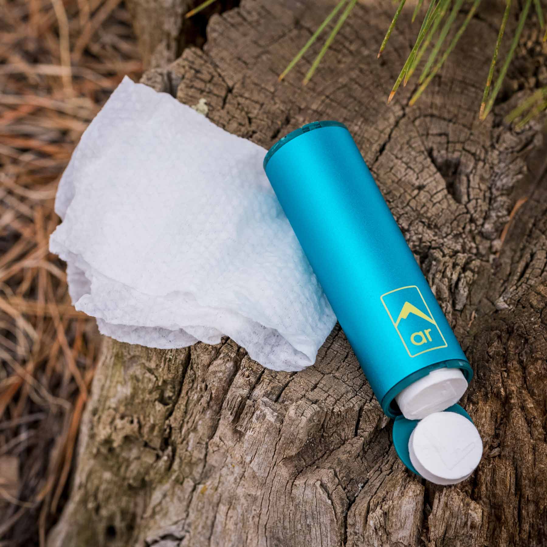 The Adventure Ready Clean Capsule in the field. One end opened showing the compressed towel as a dry puck towel. Next to it are the towels that have been uncompressed through adding water to them, laid out.