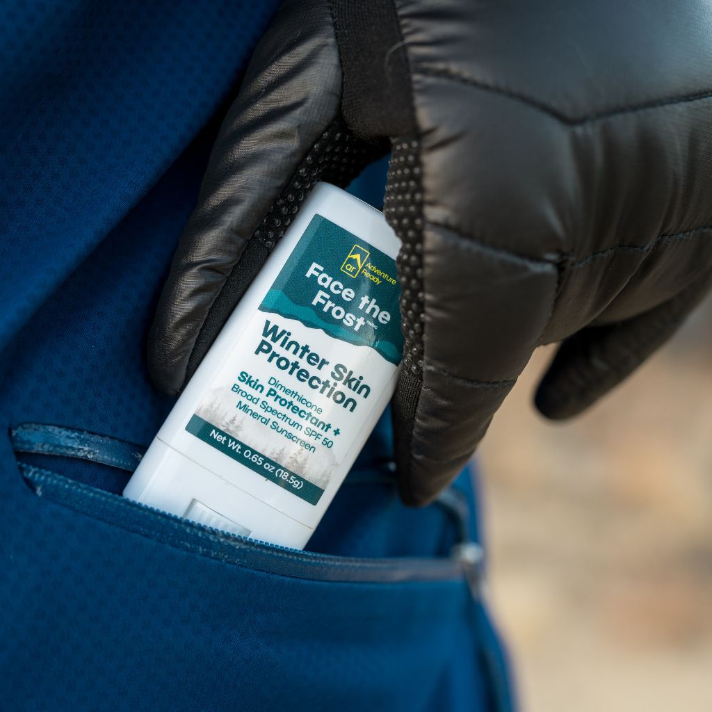 Gloved hand putting Face the Frost into a coat pocket